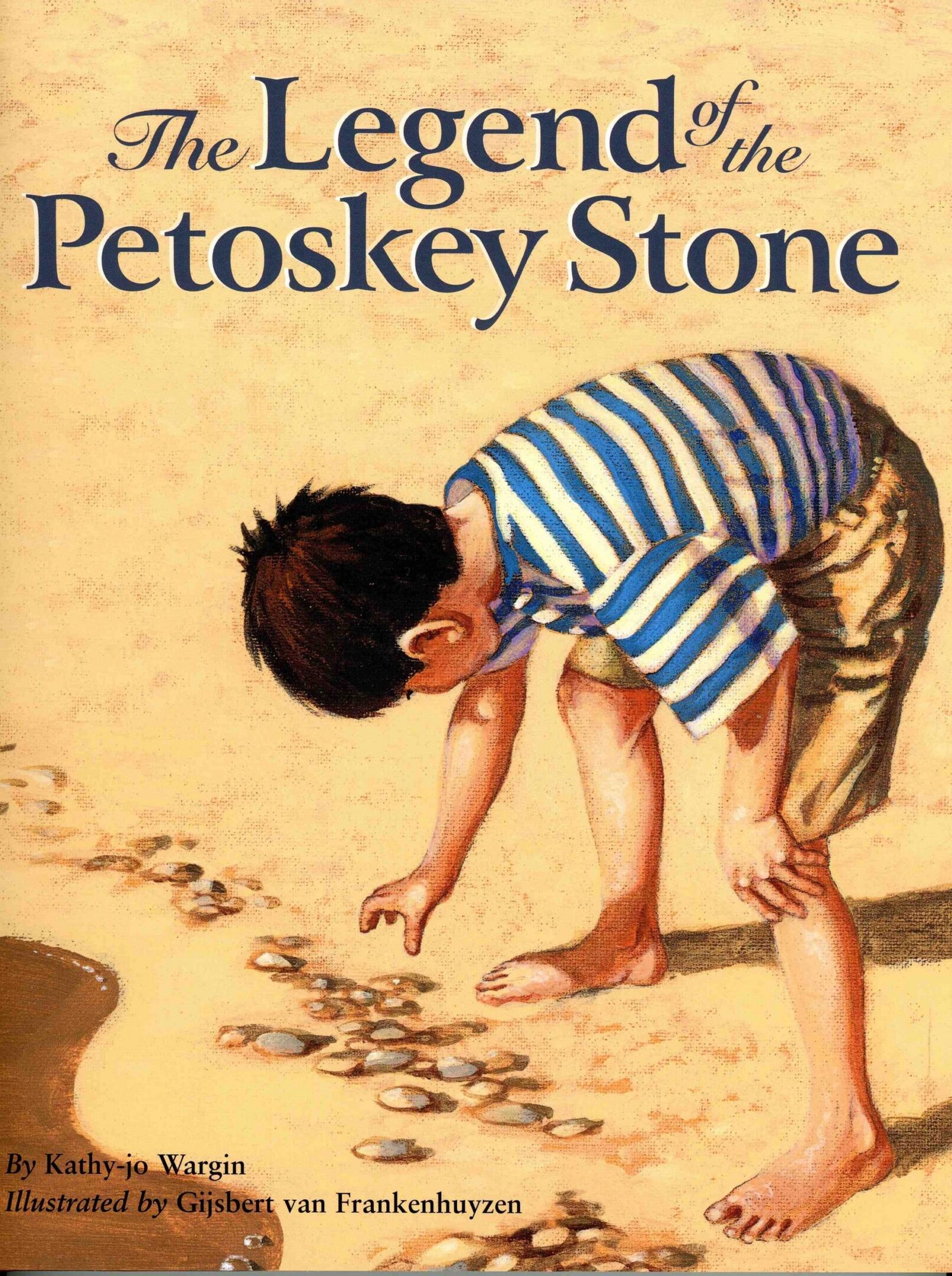 Child examining stones on a sandy beach.